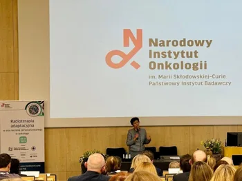 Kobieta przemawia na tle ekranu z logotypem Narodowego Instytutu Onkologii.