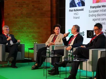 Cztery osoby siedzą na scenie podczas panelu dyskusyjnego, w tle ekran z nazwiskami.