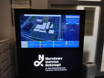 Ekran informacyjny z mapą budynków i logo Narodowego Instytutu Onkologii na dole.
