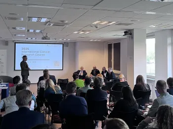 Sala konferencyjna z prelegentami i publicznością, na ekranie napis „2025 International Clinical Research Course”.