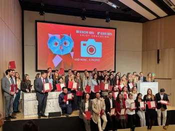 Grupa osób pozuje na scenie z certyfikatami, w tle ekran z napisem 