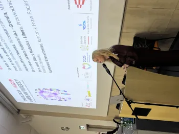 Kobieta przemawia przy mównicy na tle ekranu z tekstem o onkologii.
