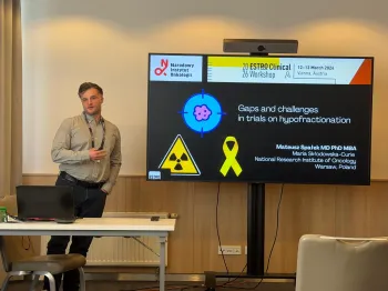 Mężczyzna prezentuje slajd z napisem: „Gaps and challenges in trials on hypofractionation”.
