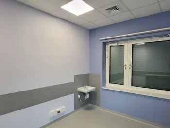 Pomieszczenie z fioletowymi ścianami, umywalką i oknem z roletą.