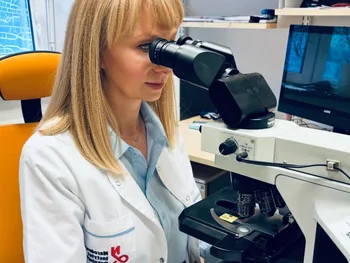 Kobieta w białym fartuchu patrzy przez mikroskop w laboratorium