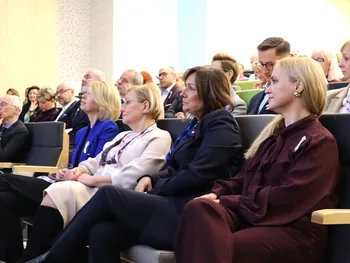 Grupa osób siedzących w audytorium, uważnie słuchających prezentacji lub wykładu.