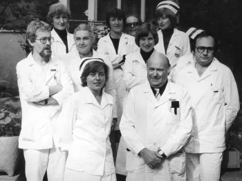 Grupa osób w białych fartuchach medycznych na zewnątrz budynku, rok 1980.