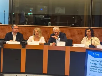Cztery osoby siedzą przy stole w sali konferencyjnej, na stole mikrofony i tabliczki z nazwiskami.