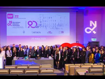 Grupa ludzi w sali konferencyjnej, w tle ekran z napisem „SOF 22 Narodowy Instytut Onkologii 90 lat”.