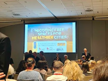 Konferencja w sali z ekranem, na którym widnieje napis: „Nicotine free spaces for healthier cities