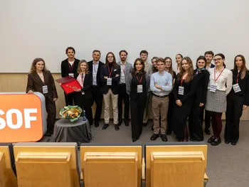Grupa osób pozuje w sali konferencyjnej, obok logo z napisem 