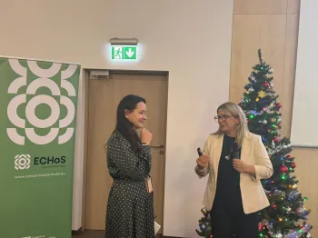 Dwie osoby rozmawiają obok choinki i roll-upu z logo ECHoS.
