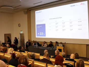 Sala konferencyjna, panel dyskusyjny, ekran z wykresem dotyczącym liczby wydanych kart DILO.