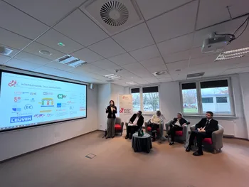 Osoby siedzące w sali konferencyjnej, jedna osoba stoi przy ekranie z prezentacją.