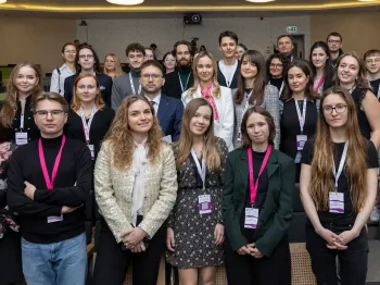 Grupa młodych dorosłych pozuje w audytorium, większość nosi identyfikatory na smyczach.
