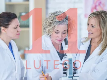 Trzy kobiety w białych fartuchach przy mikroskopie, nałożony napis: 11 LUTEGO