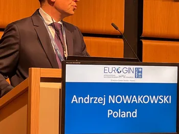 Mężczyzna w garniturze przy mównicy, na ekranie napis: 