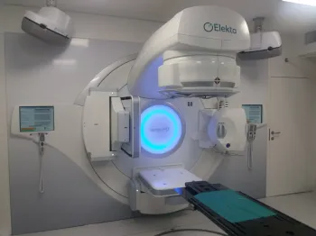 Aparat do radioterapii w nowoczesnym pomieszczeniu medycznym, na ścianie logo Elekta.